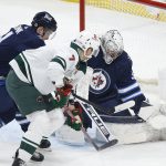 
              Winnipeg Jets goaltender Connor Hellebuyck (37) makes a save against Minnesota Wild's Nico Sturm (7) as Neal Pionk (4) defends during the first period of an NHL hockey game Wednesday, Feb. 16, 2022, in Winnipeg, Manitoba. (John Woods/The Canadian Press via AP)
            