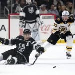 
              Los Angeles Kings right wing Dustin Brown, left, passes the puck after falling as Boston Bruins left wing Brad Marchand skates behind during the second period of an NHL hockey game Monday, Feb. 28, 2022, in Los Angeles. (AP Photo/Mark J. Terrill)
            