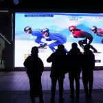 
              Residents watch a big screen showing China's team in the mixed team relay final during the short track speedskating competition at the 2022 Winter Olympics in Beijing, China, Saturday, Feb. 5, 2022. (AP Photo/Ng Han Guan)
            