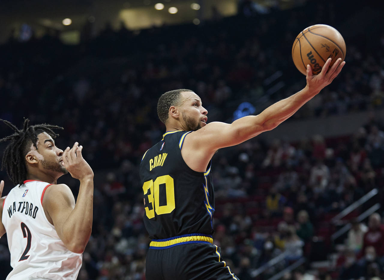 Golden State Warriors guard Stephen Curry, right, shoots in front of Portland Trail Blazers forward...