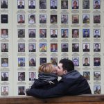 
              FILE- A couple shares a kiss at a memorial wall with photos of servicemen killed in the conflict with pro-Russian separatists in the country's east, in Kyiv, Ukraine, Tuesday, Nov. 19, 2019. More than 100,000 Russian troops are massed along the Ukrainian border in 2022, preparing for a possible invasion. Vladimir Putin's Russia has perfected the art of flouting the rules, whether the venue is the Olympic arena, international diplomacy or meddling in other countries' elections from the comfort of home. And it has suffered little consequence for its actions. (AP Photo/Efrem Lukatsky, File)
            