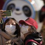 
              Residents wearing face masks to help protect from the coronavirus take a selfie with the Olympic mascot Bing Dwen Dwen decoration in Beijing, Tuesday, Feb. 8, 2022. China has ordered inhabitants of the southern city of Baise to stay home and suspended transportation links amid a surge in COVID-19 cases at least partly linked to the omicron variant. (AP Photo/Andy Wong)
            