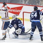
              Edmonton Oilers' Zach Hyman (18) celebrates his goal against Winnipeg Jets goaltender Connor Hellebuyck (37) and Logan Stanley (64) during the first period of an NHL hockey game in Winnipeg, Manitoba, Saturday, Feb. 19, 2022. (John Woods/The Canadian Press via AP)
            