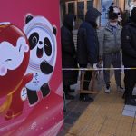 
              Residents, some with stools, line up to visit a store selling 2022 Winter Olympics memorabilia in Beijing, Monday, Feb. 7, 2022. The race is on to snap up scarce 2022 Winter Olympics souvenirs. Dolls of mascot Bing Dwen Dwen, a panda in a winter coat, sold out after buyers waited in line overnight in freezing weather. (AP Photo/Andy Wong)
            