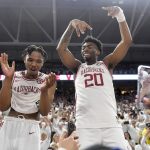 
              Arkansas players JD Notae, left), and Kamani Johnson (20) celebrate with fans after defeating Auburn 80-76 in overtime following an NCAA college basketball game Tuesday, Feb. 8, 2022, in Fayetteville, Ark. (AP Photo/Michael Woods)
            