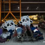 
              People sleep on benches next to cutouts of the Olympic mascot Bing Dwen Dwen at the Beijing Capital International Airport after the 2022 Winter Olympics, Monday, Feb. 21, 2022, in Beijing. (AP Photo/Jae C. Hong)
            