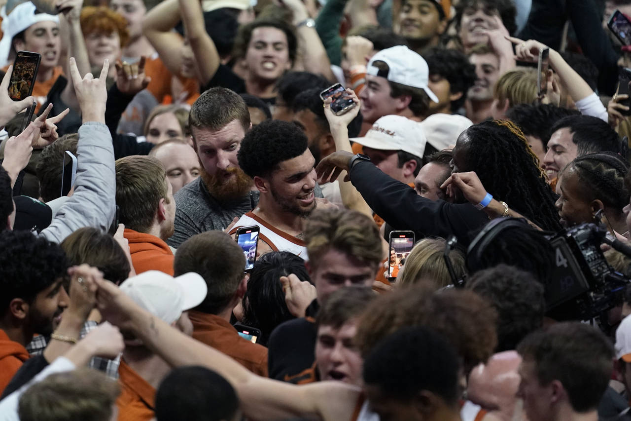Texas forward Timmy Allen, center, celebrates with fans as they storm the court after Texas' win ov...