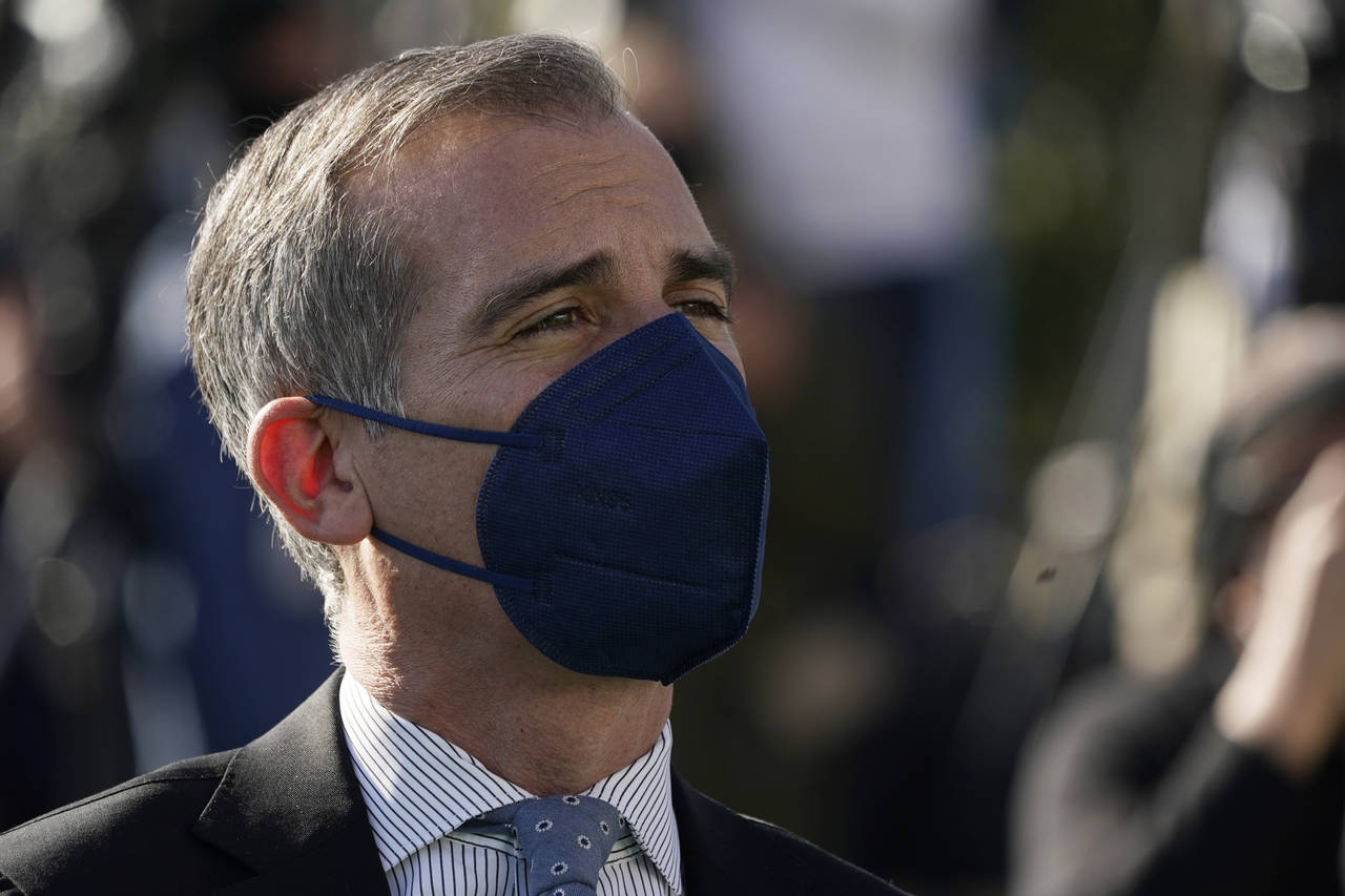 Los Angeles Mayor Eric Garcetti wears a mask as he listens to fellow speakers at a news conference ...