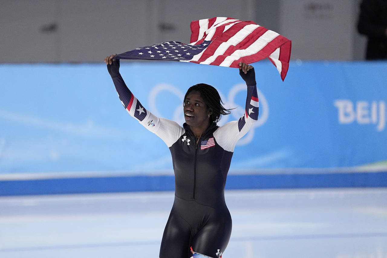 Erin Jackson of the United States hoists an American flag after winning the gold medal in the speed...
