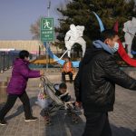 
              Residents walk by a barricaded venue which host the men's and women's ice hockey games at the 2022 Winter Olympics in Beijing, Thursday, Feb. 10, 2022. The possibility of a large outbreak in the Olympic bubble, potentially sidelining athletes from competitions, has been a greater fear than any leakage into the rest of China. (AP Photo/Andy Wong)
            