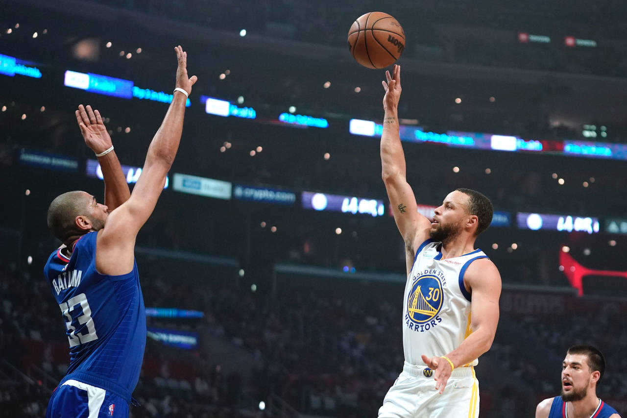 Golden State Warriors guard Stephen Curry shoots as Los Angeles Clippers forward Nicolas Batum defe...