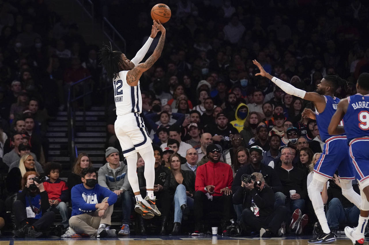 Memphis Grizzlies' Ja Morant, left, makes a shot during the first half of an NBA basketball game ag...