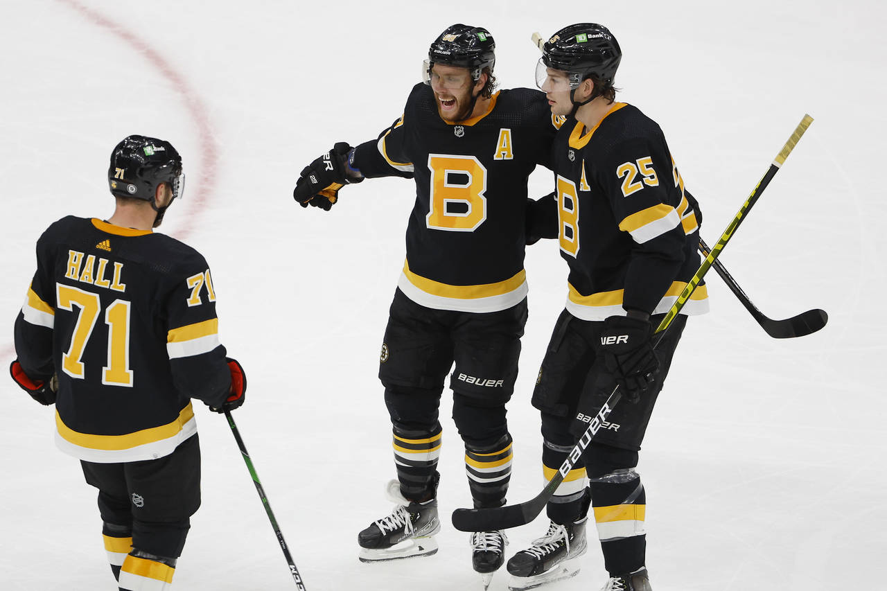 Boston Bruins' David Pastrnak is congratulated by Brandon Carlo (25) and Taylor Hall after scoring ...