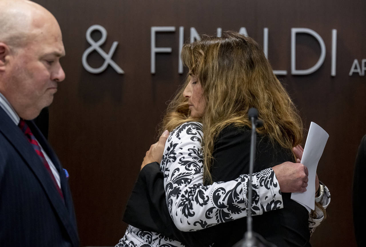 Survivors Kara Cagle, center, and Julie Wallach embrace during a news conference where attorney Joh...