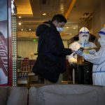 
              A hotel worker in protective gear helps a guest pay for his purchase at the Shangri-La Hotel at the 2022 Winter Olympics, Wednesday, Feb. 16, 2022, in Beijing. (AP Photo/Jae C. Hong)
            