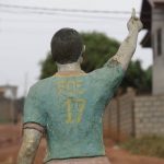 
              A man walks past the statue of late Cameroonian soccer star Marc-Vivien Foé, outside his abandoned soccer academy in Yaounde, Cameroon, Wednesday Feb. 2, 2022. The late Cameroon and Manchester City soccer star Marc-Vivien Foé had a dream to build a sports complex and school in his hometown of Yaounde. He never got to finish it after collapsing on a field while playing for his country in 2003 and dying of a heart condition at the age of 28. (AP Photo/Sunday Alamba)
            