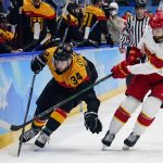 
              Germany's Tom Kuhnhackl (34) and China's Jieke Kailiaosi (Jake Chelios) (7) chase after the puck during a preliminary round men's hockey game at the 2022 Winter Olympics, Saturday, Feb. 12, 2022, in Beijing. (AP Photo/Matt Slocum)
            