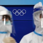
              The Olympic rings are seen behind workers staged in protective equipment at the National Indoor Stadium at the 2022 Winter Olympics, Tuesday, Feb. 1, 2022, in Beijing. (AP Photo/Matt Slocum)
            