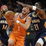 
              Phoenix Suns guard Devin Booker (1) drives as New Orleans Pelicans forward Brandon Ingram (14) and forward Tony Snell (21) defend during the second half of an NBA basketball game, Friday, Feb. 25, 2022, in Phoenix. (AP Photo/Matt York)
            