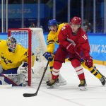 
              Russian Olympic Committee's Sergei Plotnikov, right, controls the puck in front of Sweden's Pontus Holmberg (29) and Sweden goalkeeper Lars Johansson, left, during a men's semifinal hockey game at the 2022 Winter Olympics, Friday, Feb. 18, 2022, in Beijing. (AP Photo/Petr David Josek)
            