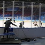 
              A member of the broadcast crew installs cable as Canada's women's hockey team practice on the ice at the 2022 Winter Olympics, Jan. 30, 2022, in Beijing. (AP Photo/Jeff Roberson)
            