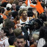 
              Texas forward Tre Mitchell, center, celebrates with fans as they storm the court after Texas' win over Kansas in an NCAA college basketball game, Monday, Feb. 7, 2022, in Austin, Texas. (AP Photo/Eric Gay)
            