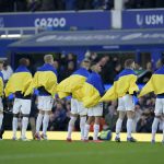 
              FILE - Everton players hold Ukrainian flags before the English Premier League soccer match between Everton and Manchester City at Goodison Park in Liverpool, England, Saturday, Feb. 26, 2022. (AP Photo/Jon Super, File)
            