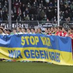 
              At the start of the match, the players of both teams hold a Ukrainian flag with the inscription "Stop War. We against war." prior the Bundesliga soccer match between Greuther Fuerth and 1. FC Cologne in Fuerth, Germany, Saturday, Feb. 26, 2022. (Daniel Karmann/dpa via AP)
            
