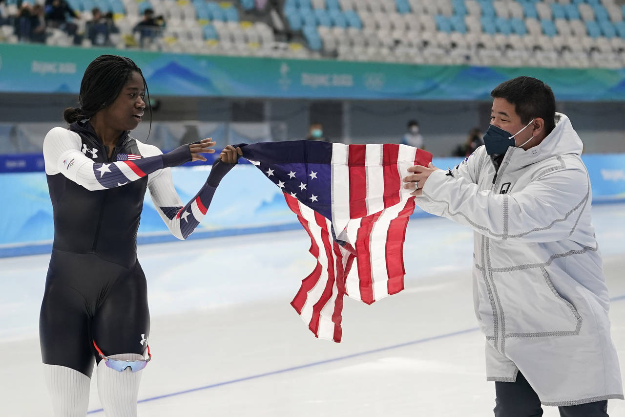 Erin Jackson of the United States holds up an American flag with coach Ryan Shimabukuro after winni...