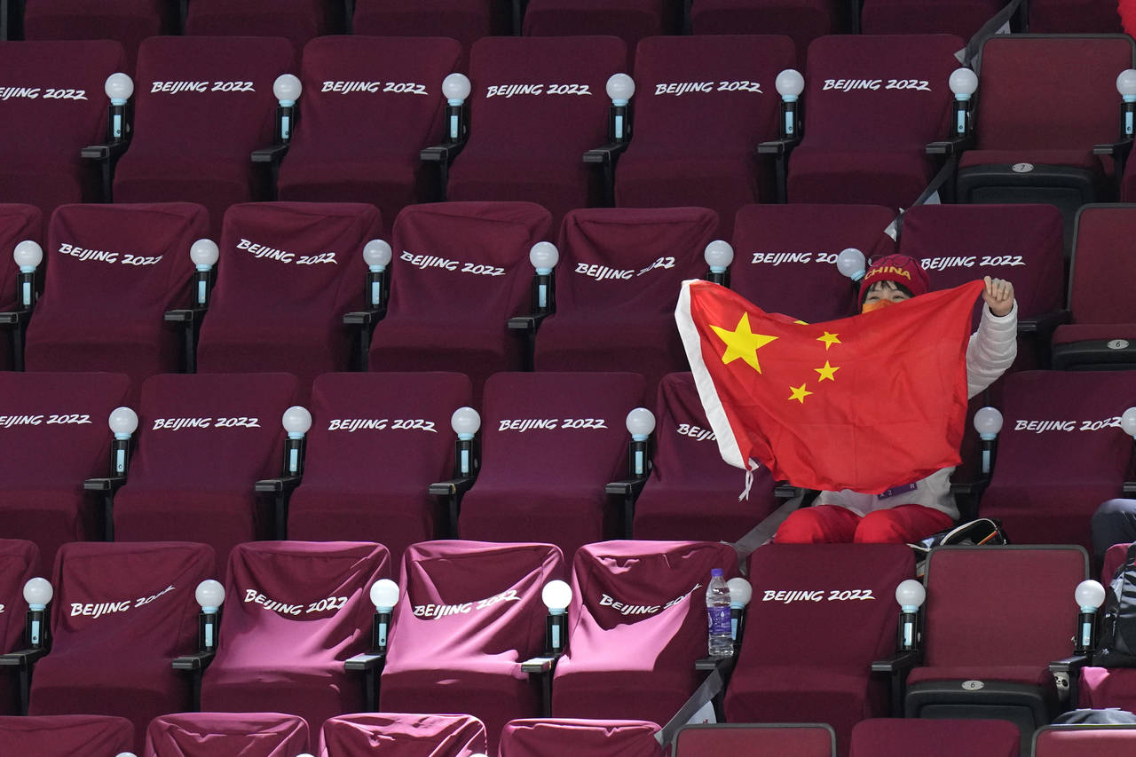 A spectator waves a Chinese flag during a preliminary round women's hockey game between China and C...