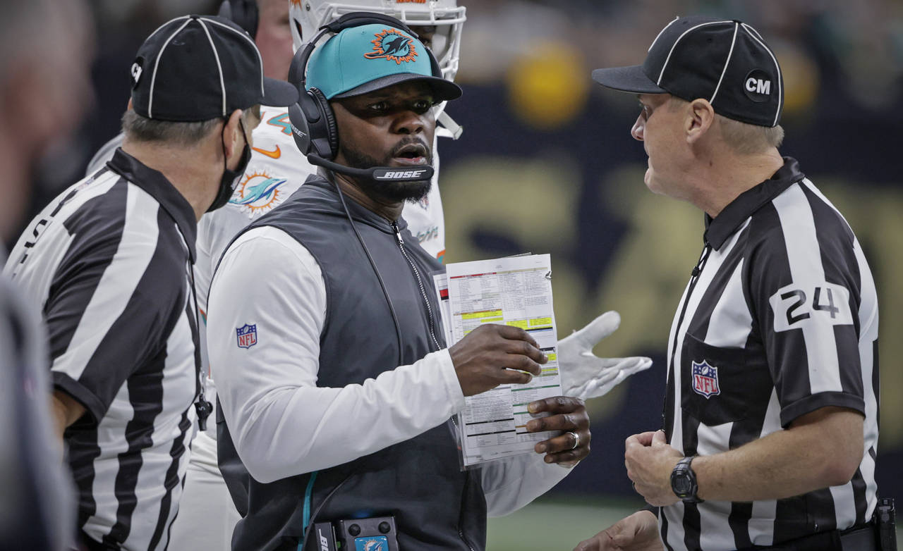 FILE - Miami Dolphins head coach Brian Flores, center, talks to down judge David Oliver (24) during...