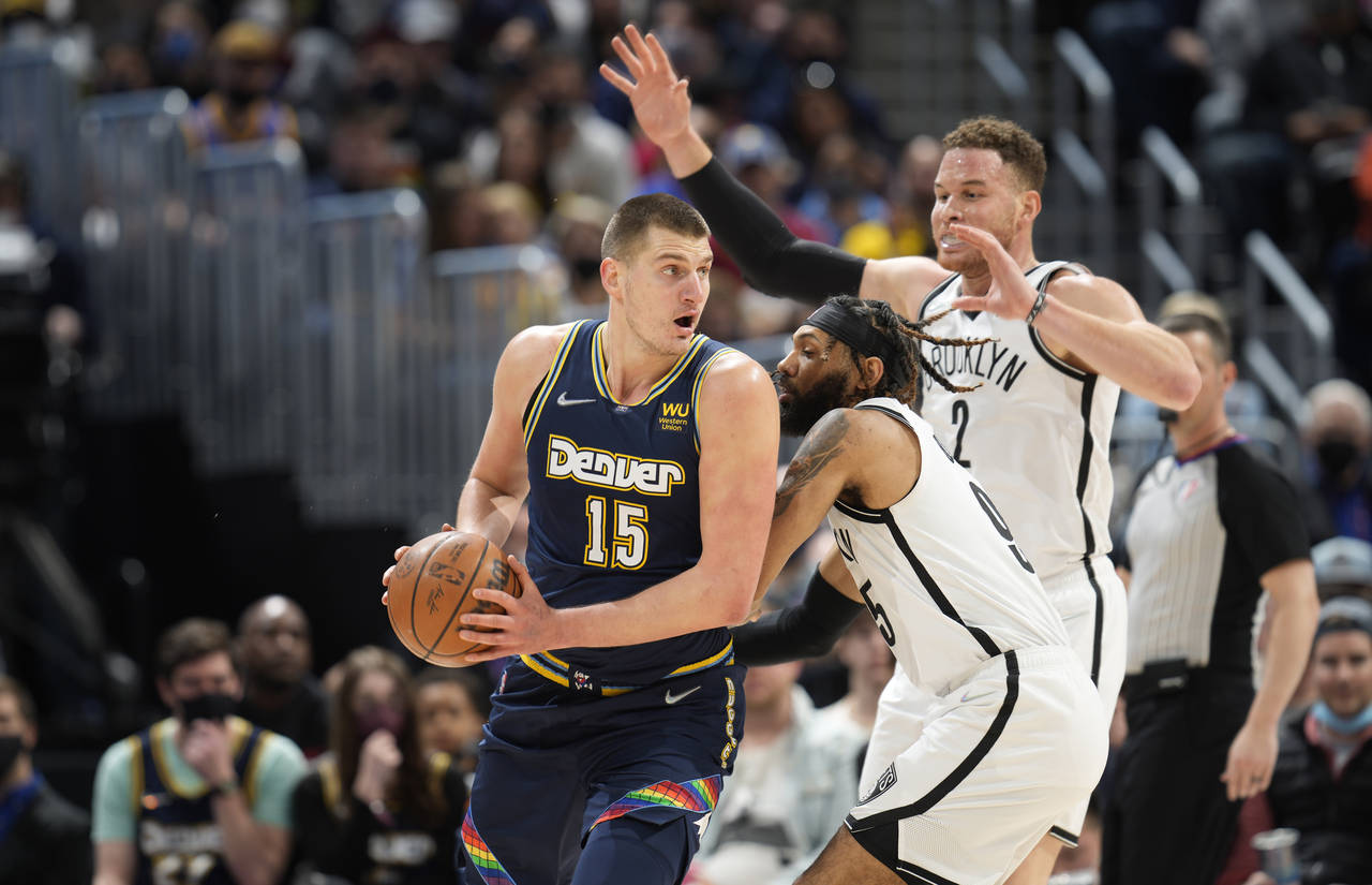 Denver Nuggets center Nikola Jokic, left, looks to pass the ball as Brooklyn Nets guard DeAndre' Be...