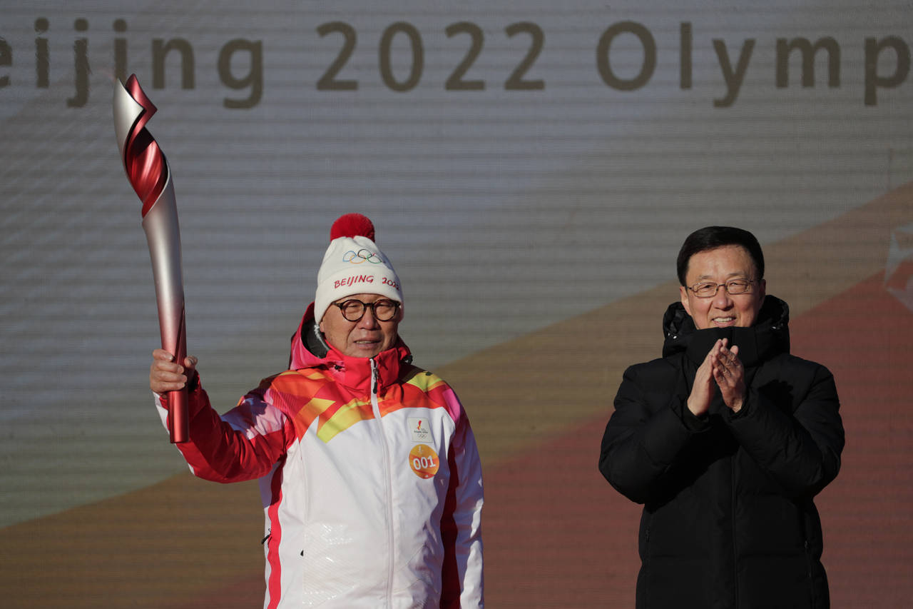 First Torch bearer Luo Zhihuan holds up the torch after receiving it from Chinese Vice Premier Han ...