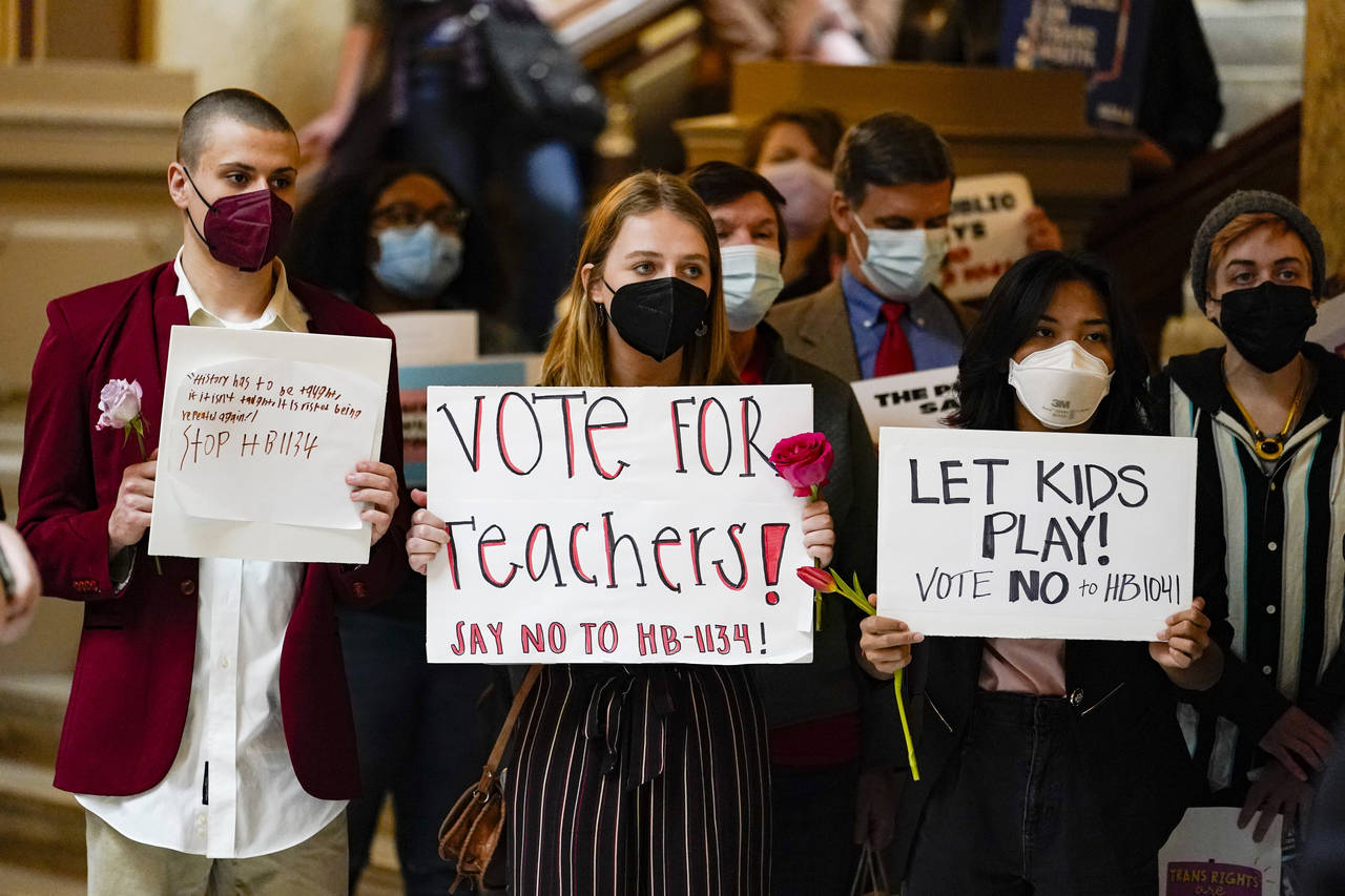 Protesters carry signs at a rally held in opposition to bills being considered at the Statehouse in...