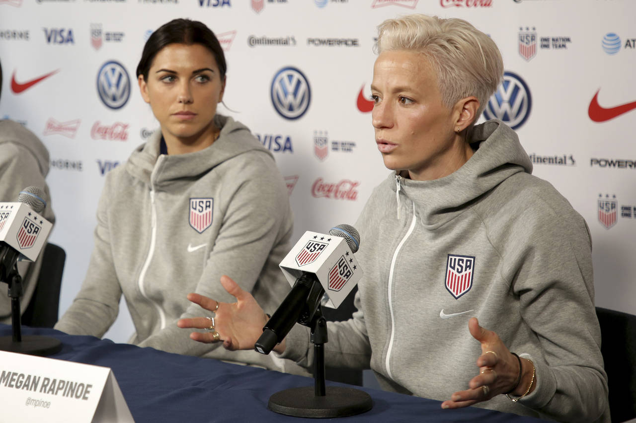 FILE - United States women's national soccer team member Alex Morgan, left, listens as teammate Meg...