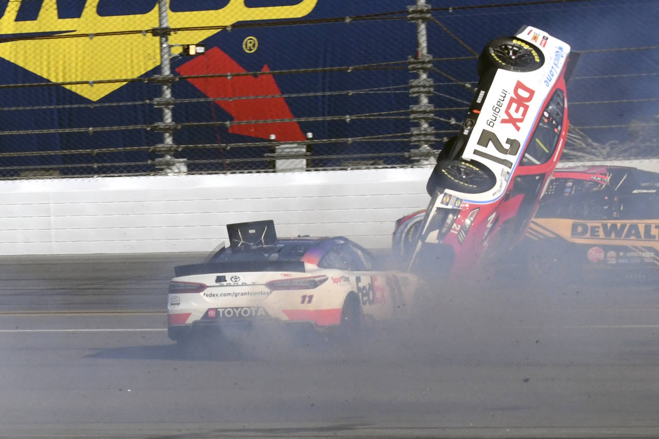 Harrison Burton (21) goes airborne in a crash as he gets caught between Denny Hamlin, left, and Chr...