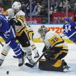 
              Pittsburgh Penguins goaltender Tristan Jarry (35) makes a save as Toronto Maple Leafs forward Auston Matthews (34) is hit by Penguins defenseman Kris Letang (58) during the second period of an NHL hockey game Thursday, Feb. 17, 2022, in Toronto. (Nathan Denette/The Canadian Press via AP)
            