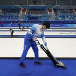 
              A volunteer vacuums the floor at the National Aquatics Center, a venue for curling events at the 2022 Winter Olympics, Saturday, Jan. 29, 2022, in Beijing. (AP Photo/Jae C. Hong)
            