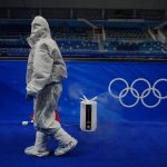 
              A person in protective gear walks by an air purifier after emptying water at the curling venue ahead of the Beijing Winter Olympics Tuesday, Feb. 1, 2022, in Beijing. (AP Photo/Brynn Anderson)
            