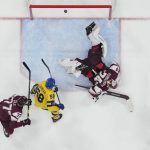 
              Latvia goalkeeper Ivars Punnenovs (74) dives for the puck as Sweden's Lucas Wallmark, not shown, scores a goal during a preliminary round men's hockey game at the 2022 Winter Olympics, Thursday, Feb. 10, 2022, in Beijing. In front of Punnenovs are Sweden's Anton Lander (58), and Latvia's Kristaps Roberts Zile (77) and Roberts Mamcics (55). (AP Photo/Matt Slocum)
            