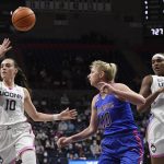 
              Connecticut's Nika Mühl (10) passes over DePaul's Lexi Held (10) to Connecticut's Aaliyah Edwards (3) during the first half of an NCAA college basketball game Friday, Feb. 11, 2022, in Storrs, Conn. (AP Photo/Jessica Hill)
            