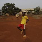 
              David Nonga, plays with a ball on the field outside the late Cameroonian soccer star Marc-Vivien Foé's abandoned soccer academy in Yaounde, Cameroon, Wednesday Feb. 2, 2022. The late Cameroon and Manchester City soccer star Marc-Vivien Foé had a dream to build a sports complex and school in his hometown of Yaounde. He never got to finish it after collapsing on a field while playing for his country in 2003 and dying of a heart condition at the age of 28.  (AP Photo/Sunday Alamba)
            