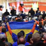 
              A fan holds a Ukrainian flag during a moment of silence before an NCAA college basketball game between Syracuse and Duke in Syracuse, N.Y., Saturday, Feb. 26, 2022. (AP Photo/Adrian Kraus)
            
