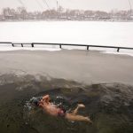 
              A man swims in the half-frozen water at the Shichahai Lake during a snow fall in Beijing, Sunday, Feb. 13, 2022. According to some of the local residents, swimming in the freezing water leads to health. (AP Photo/Andy Wong)
            
