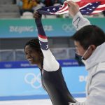 
              Erin Jackson of the United States skates on the ice hoisting an American flag with her coach Ryan Shimabukuro after winning the gold medal in the speedskating women's 500-meter race at the 2022 Winter Olympics, Sunday, Feb. 13, 2022, in Beijing.
            