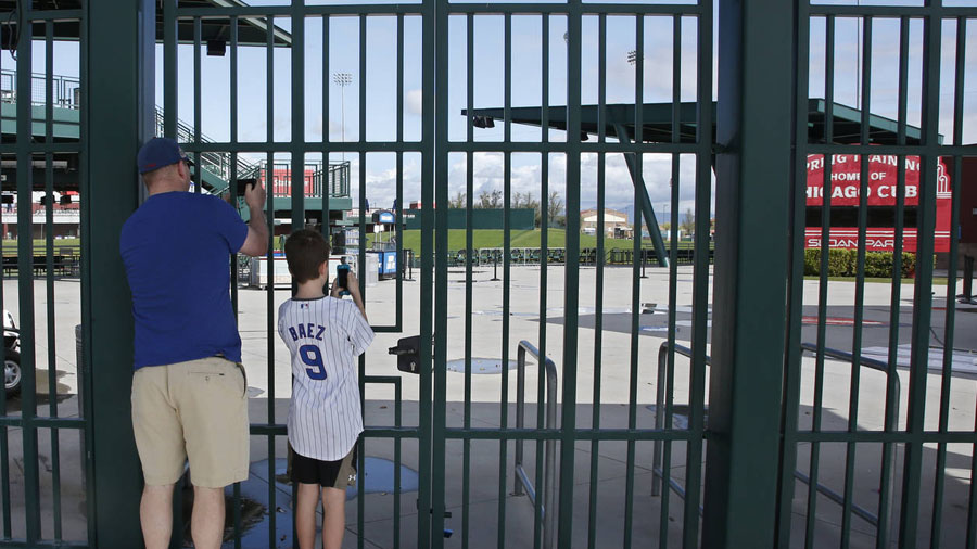 Cubs fans take photos through the locked gates at Sloan Park in Mesa, Ariz. (AP Photo/Sue Ogrocki, ...