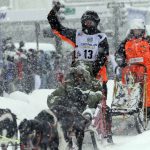 
              Hanna Lyrek, a musher from Alta, Norway, waves to fans while taking her sled dogs through a snowstorm in downtown Anchorage, Alaska, on Saturday, March 5, 2022, during the ceremonial start of the Iditarod Trail Sled Dog Race. The competitive start of the nearly 1,000-mile race will be held March 6, 2022, in Willow, Alaska, with the winner expected in the Bering Sea coastal town of Nome about nine days later. (AP Photo/Mark Thiessen)
            