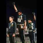 
              FILE - United States athletes Tommie Smith, center, and John Carlos raise their gloved fists after Smith received the gold and Carlos the bronze for the 200-meter run at the Summer Olympic Games in Mexico City, Oct. 16, 1968. The International Olympic Committee has always been political, from the sheikhs and royals in its membership to a seat at the United Nations to pushing for peace talks between the Koreas. But Russia’s invasion of Ukraine three weeks ago exposed its irreconcilable claims of “political neutrality.” (AP Photo/File)
            