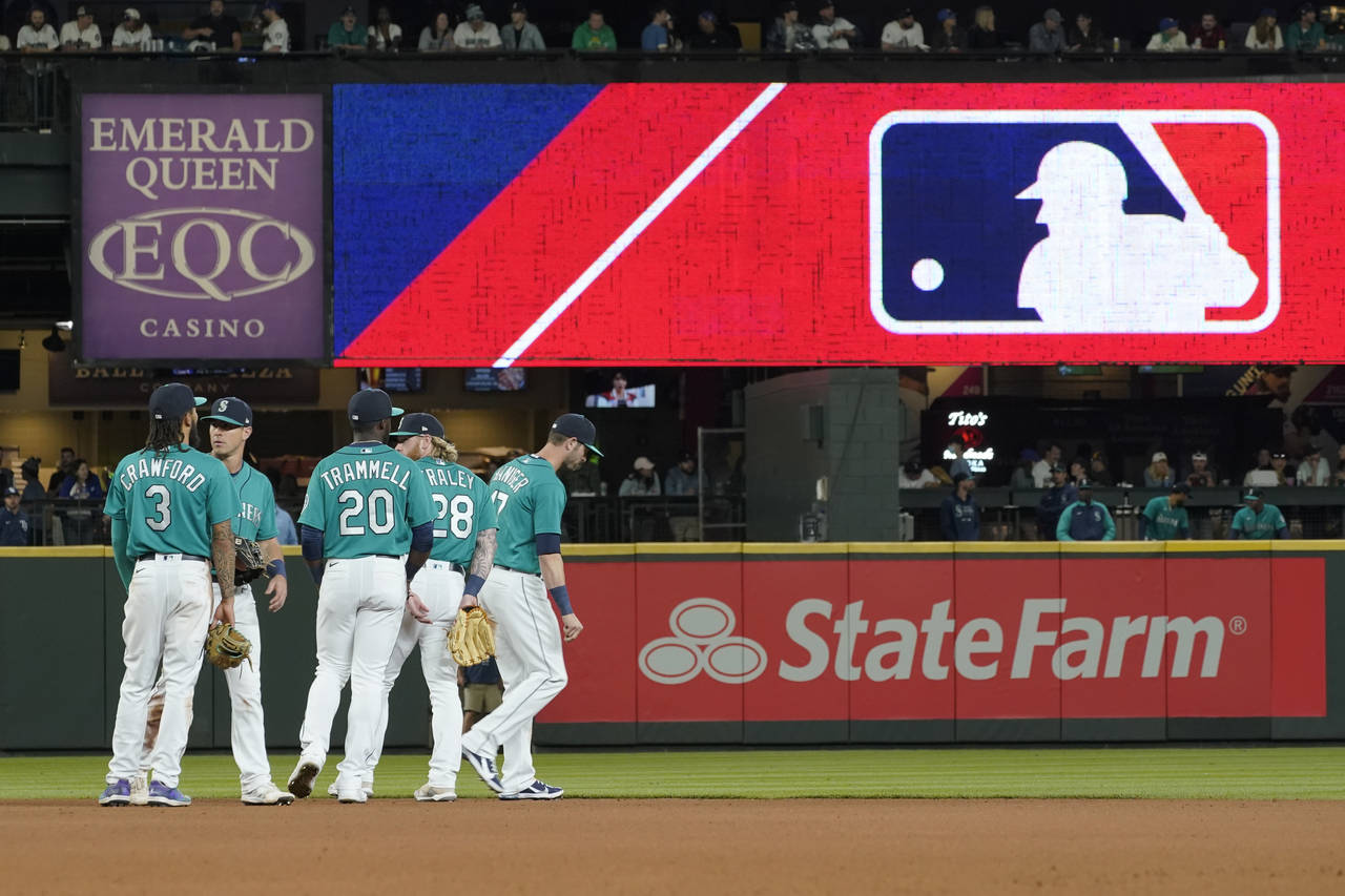 FILE - Seattle Mariners gather as the MLB logo is shown during a review of an attempted catch by ri...