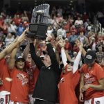
              North Carolina State head coach Wes Moore holds the trophy with his players following an NCAA college basketball championship game against Miami at the Atlantic Coast Conference women's tournament in Greensboro, N.C., Sunday, March 6, 2022. (AP Photo/Gerry Broome)
            